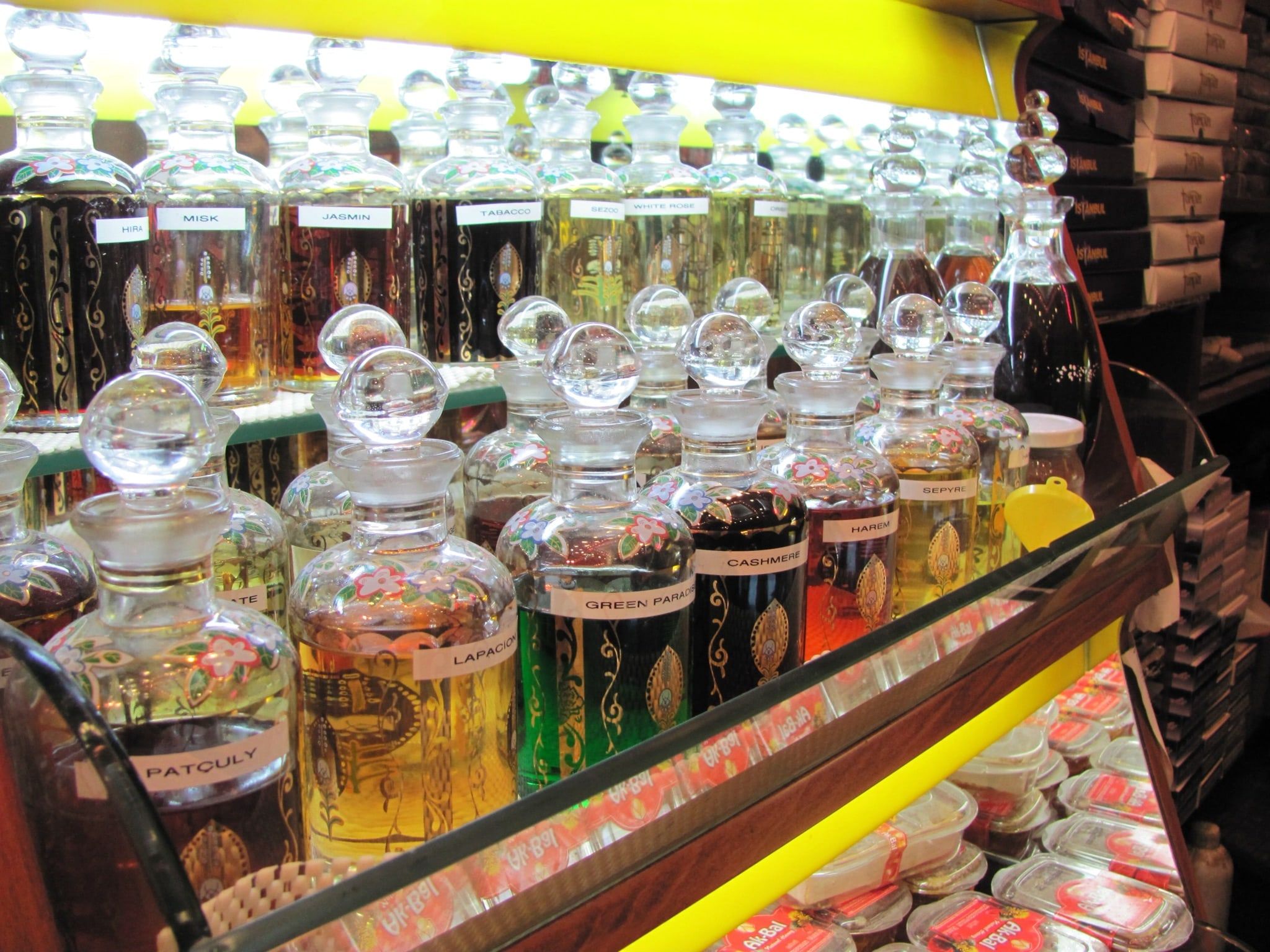 Frascos de perfume de cristal tallado con esencias de distintos colores expuestos en las baldas de una perfumería