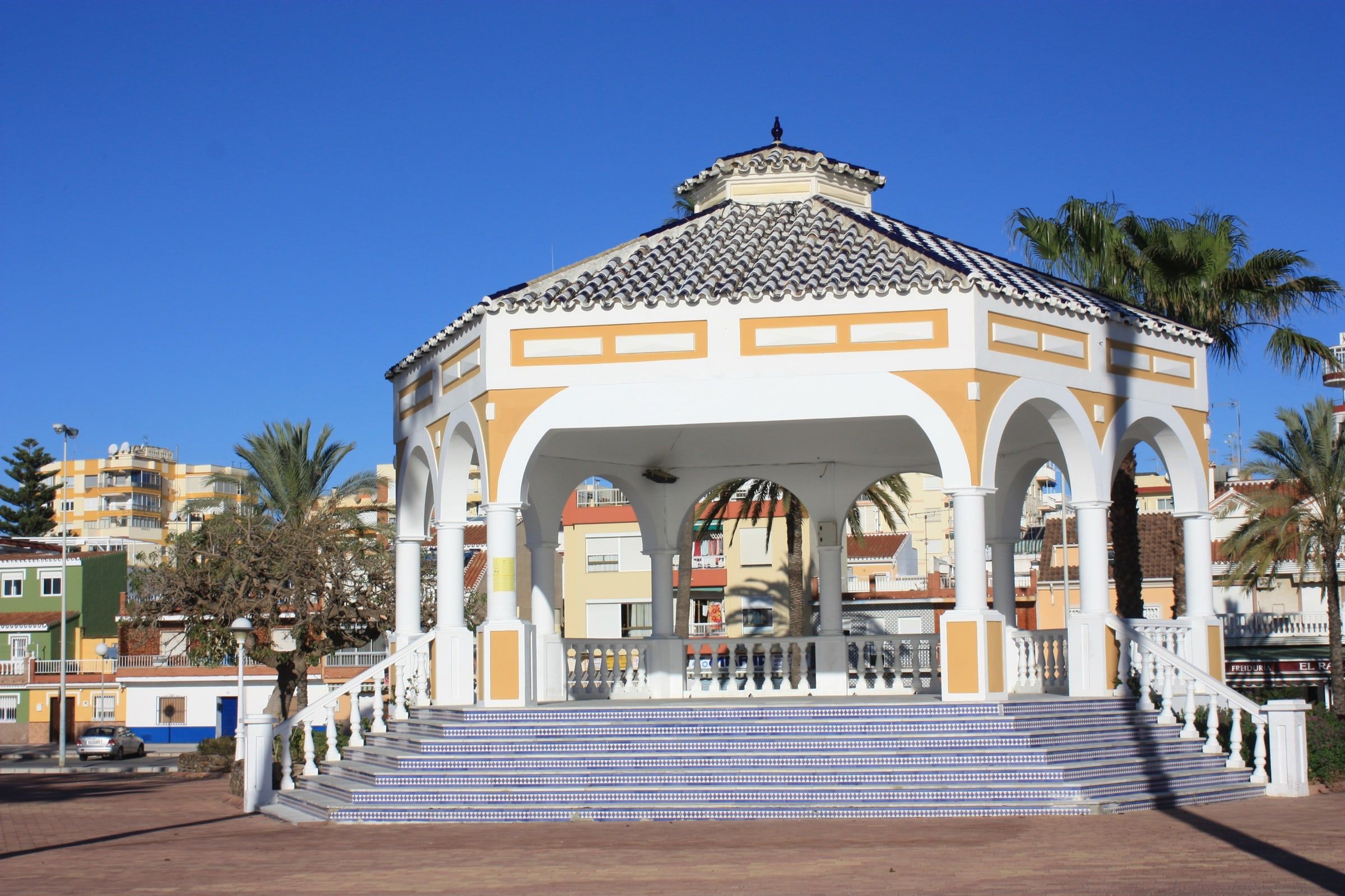 Templete blanco del paseo de Torre del Mar entre palmeras