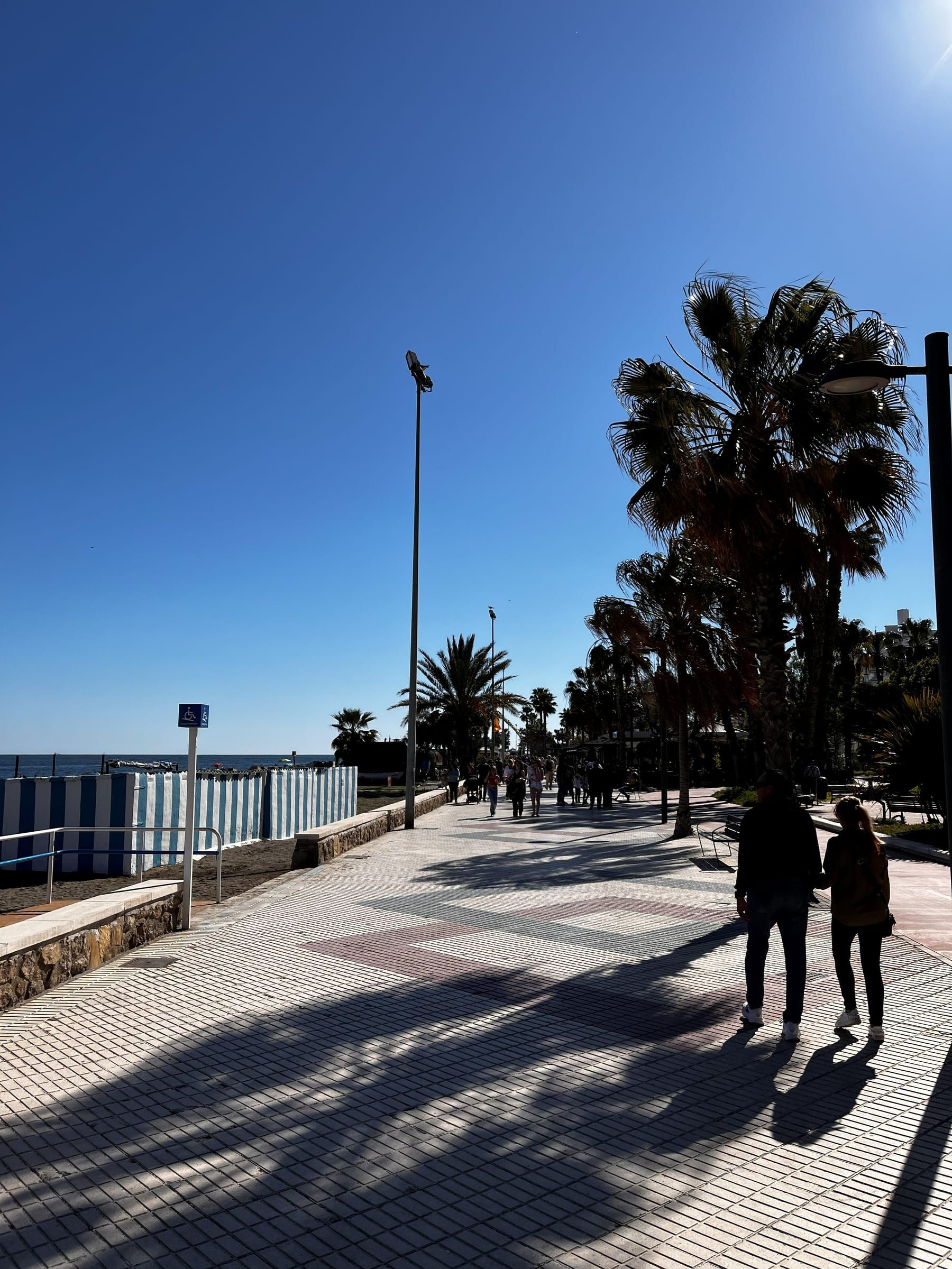 Paseo marítimo de Torre del Mar en un día despejado, con su pavimento de dibujos, palmeras y el mar a un lado