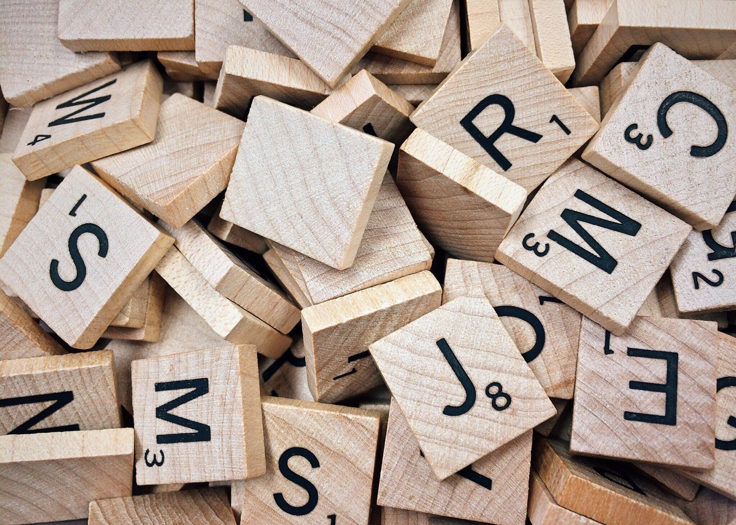 Fichas de madera con letras sueltas amontonadas, como las que se usan en juegos de palabras y ejercicios de lenguaje