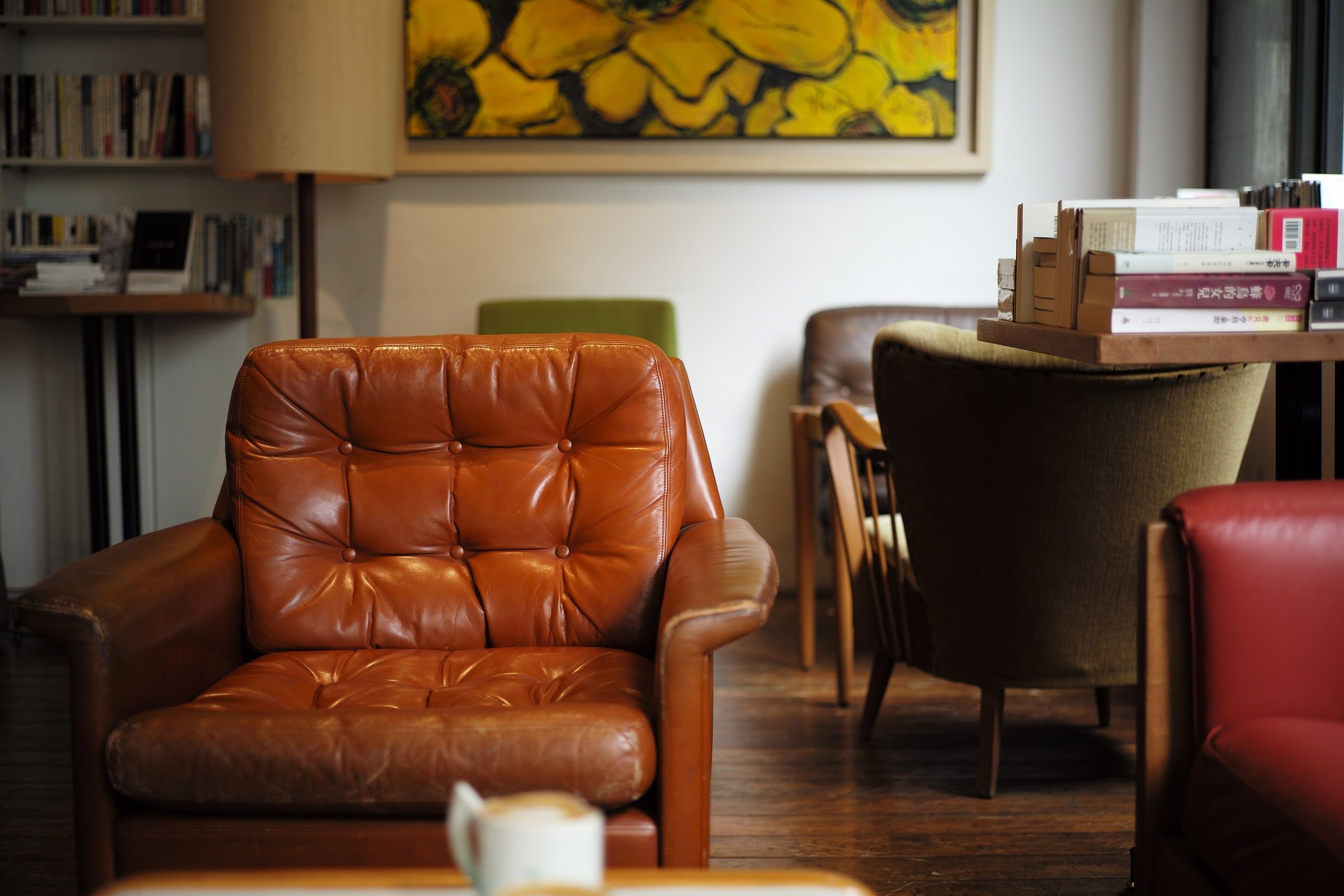 Sillón de cuero marrón en una sala tranquila y acogedora con estanterías, lámpara de pie y luz cálida, como una consulta