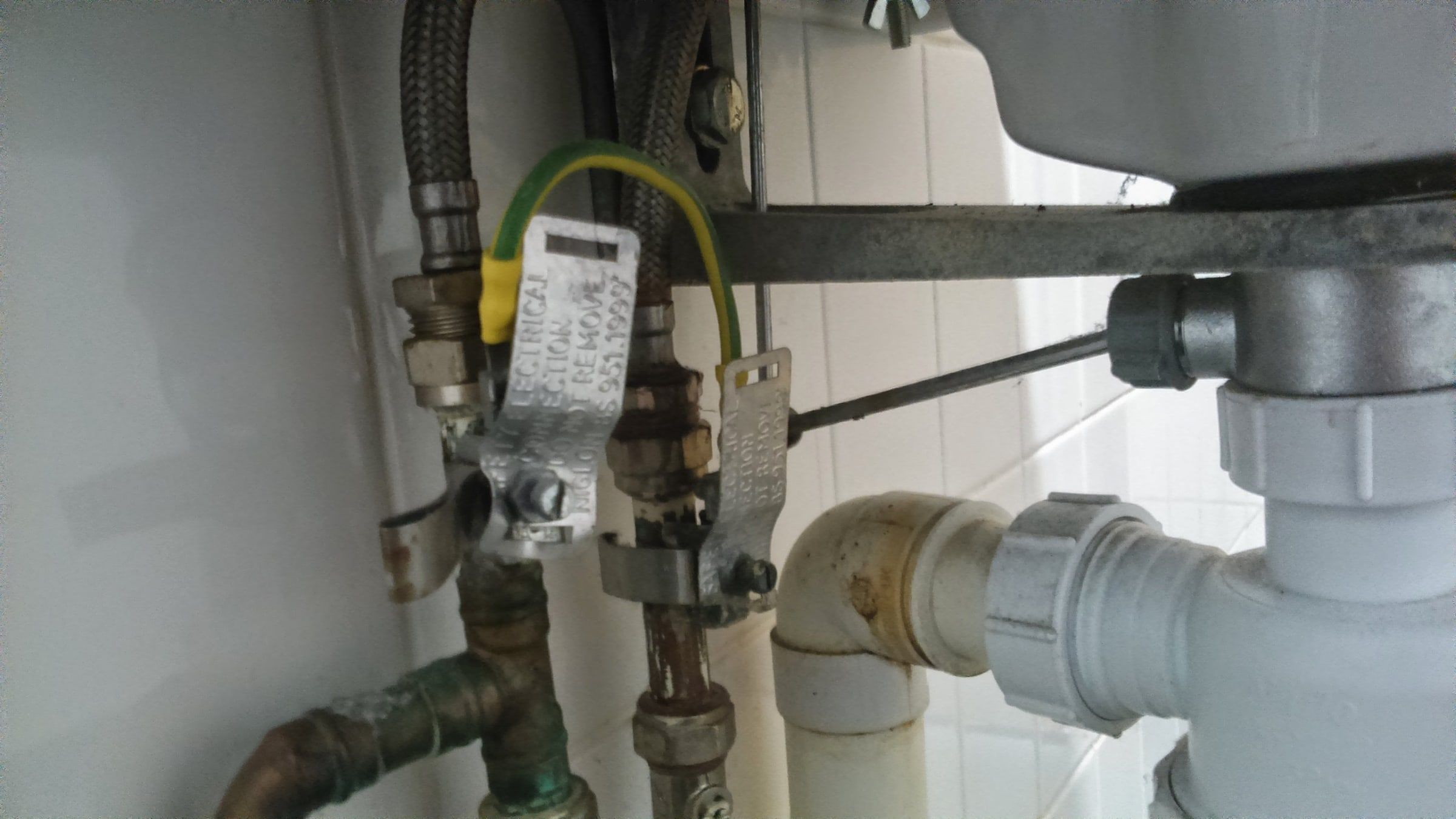 Tuberías, llaves de paso y desagüe bajo el fregadero de una cocina, la instalación que revisa un fontanero